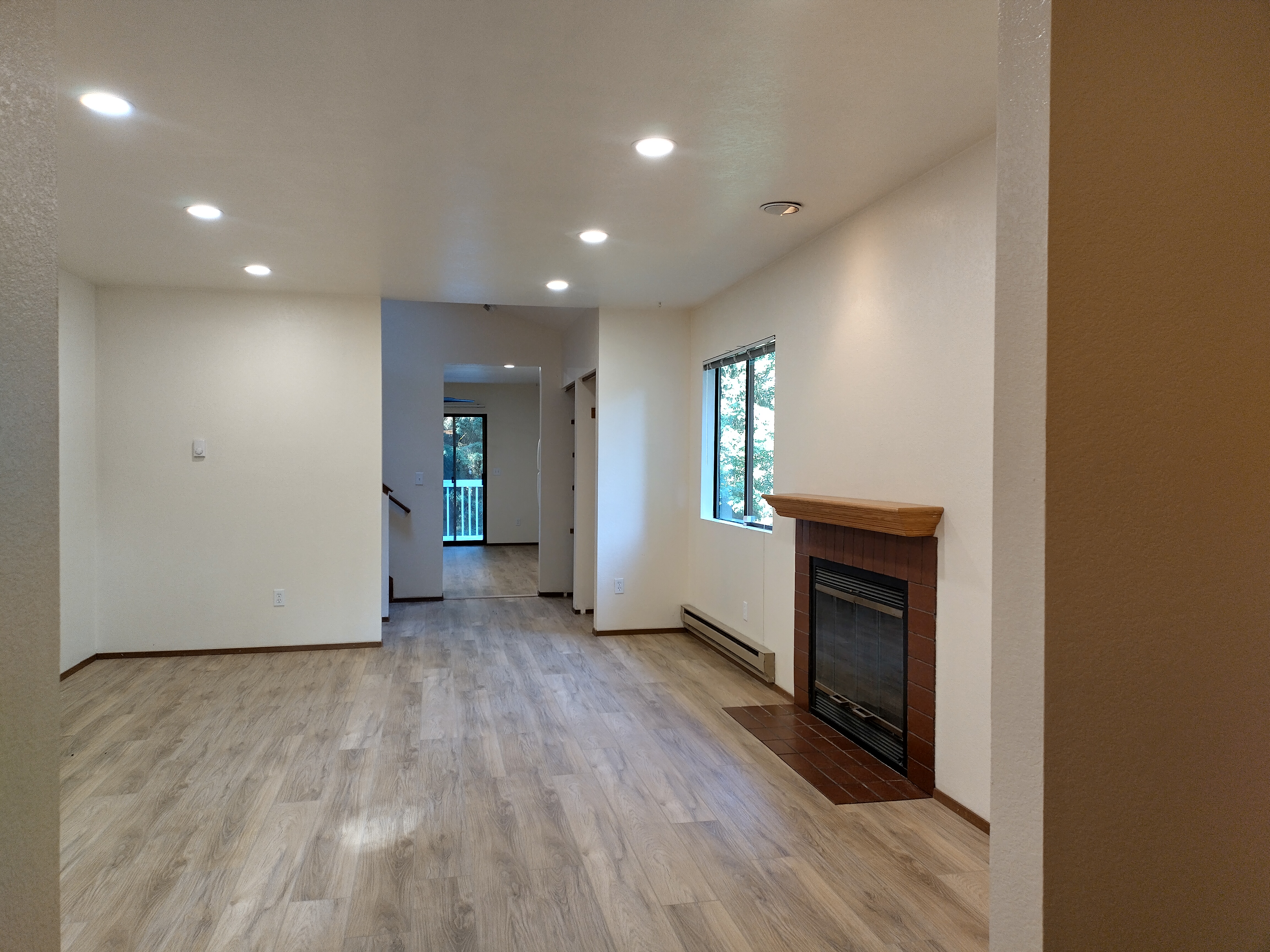 Living room after — new LVP flooring installed, same fireplace view