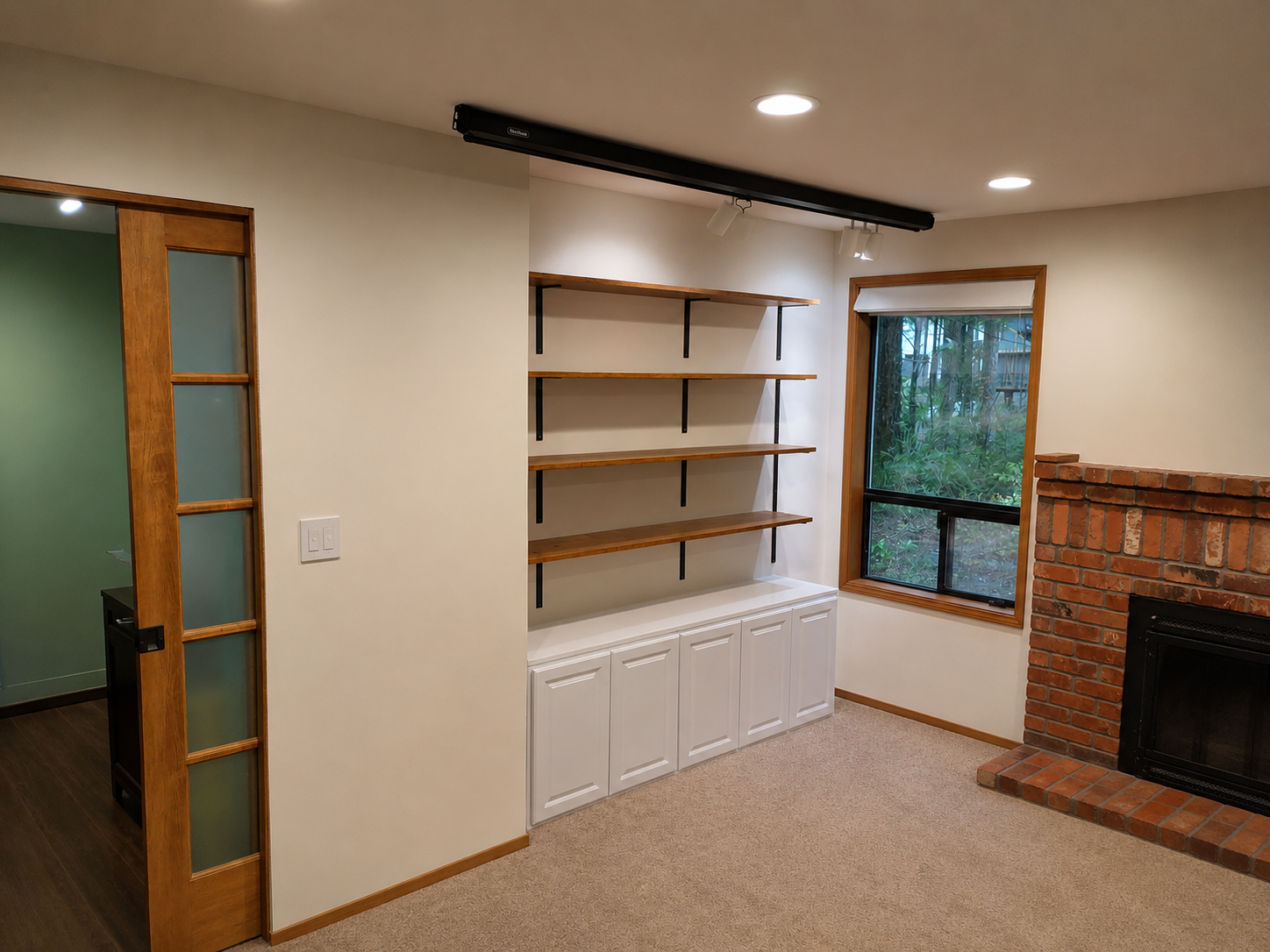 Custom stained wood built-in shelving with lower cabinet, track lighting above